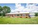 Well-maintained brick home with white metal roof, manicured lawn, and separate two car garage at 765 York Institute Rd, Hiddenite, NC 28636