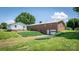 Rear exterior showcasing a brick house with a garage door, a grassy yard, and surrounding mature trees at 765 York Institute Rd, Hiddenite, NC 28636