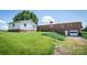 The home's rear with a brick facade, garage door, and green lawn is complemented by mature trees and open space at 765 York Institute Rd, Hiddenite, NC 28636