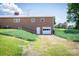 Rear exterior featuring a brick facade, a garage door, and an expansive green lawn, with a gentle slope at 765 York Institute Rd, Hiddenite, NC 28636