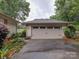 A two car garage with neutral colored doors surrounded by green landscaping at 8 Sunrise Point Rd, Lake Wylie, SC 29710