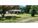 Traditional one-story home featuring a covered entryway, green lawn, and mature trees at 8000 Chapman St, Charlotte, NC 28216