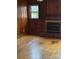 Cozy room featuring wood paneling, hardwood floors, window, and a classic brick fireplace at 8000 Chapman St, Charlotte, NC 28216