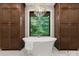 A luxurious bathroom with a soaking tub surrounded by dark wood storage and tile walls at 8066 Edgewater Dr # 103, Norwood, NC 28128