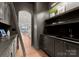 A butler's pantry with dark gray cabinets, shelves, and a sink, creating a transitional space at 8066 Edgewater Dr # 103, Norwood, NC 28128