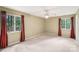 Spacious bedroom with two large windows draped with red curtains, allowing ample natural light at 8117 Rising Meadow Rd, Charlotte, NC 28277