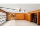Spacious garage featuring wood paneled walls, open garage door, multiple storage options and work area at 8117 Rising Meadow Rd, Charlotte, NC 28277