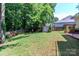 Wide view of the spacious backyard showcasing the storage shed and cozy shaded seating area with lush green lawn at 10419 Chelsea Bay Dr, Charlotte, NC 28278