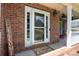 Inviting front door with glass, welcome sign, and covered porch, creating a warm entry to the brick home at 132 Parkside Ln, Mooresville, NC 28117