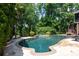 Sparkling pool surrounded by lush landscaping, mature trees, and a stone patio at 132 Parkside Ln, Mooresville, NC 28117