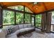 Enclosed sunroom featuring a wood ceiling, comfortable wicker furniture, and views of mature trees at 132 Parkside Ln, Mooresville, NC 28117
