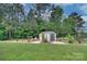 Backyard featuring a storage shed, lush greenery, and a charming outdoor seating area at 1327 Springlake Rd, York, SC 29745