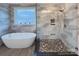 Bright bathroom featuring a soaking tub, glass-enclosed shower with pebble floor, and stone tile at 1327 Springlake Rd, York, SC 29745