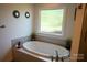 Soaking tub beneath a window providing natural light for a relaxing bathroom at 150 Wordsworth Way, Mooresville, NC 28115