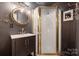 This bathroom features a shower with glass door, unique vanity with brass hardware and a round mirror at 2507 Connemara Dr, Matthews, NC 28105