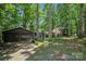 View of a detached two-car garage and home exterior surrounded by mature trees at 2507 Connemara Dr, Matthews, NC 28105