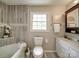 Bathroom featuring a toilet, and vanity adjacent to the tub with marble tile at 2666 Hill Ln, Gastonia, NC 28054