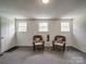 Living room has two wicker chairs, carpet flooring, and a white door at 2666 Hill Ln, Gastonia, NC 28054
