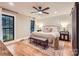 This primary bedroom features wood floors, a neutral color palette, and a ceiling fan for added comfort at 3214 Tilley Morris Rd, Matthews, NC 28105