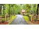 View of the gated driveway leading up to a beautiful home surrounded by lush greenery at 3214 Tilley Morris Rd, Matthews, NC 28105