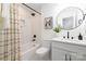 Beautiful bathroom featuring white marble tile, dark hardware, round mirror, and tub with shower at 4017 Sulkirk Rd, Charlotte, NC 28210