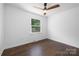 This bedroom offers dark hardwood floors, a ceiling fan, and a bright window showcasing outdoor greenery at 4017 Sulkirk Rd, Charlotte, NC 28210