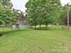 Beautifully landscaped backyard with mature trees, green grass, and a storage shed at 407 S Buckoak St, Stanley, NC 28164