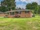 Charming brick home boasts a manicured lawn, mature trees, and classic black shutters, enhancing its curb appeal at 407 S Buckoak St, Stanley, NC 28164