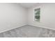 This bedroom features neutral walls, gray carpet, and a window with bright, natural light at 463 Hunton Forest Nw Dr, Concord, NC 28027