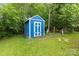 Charming blue storage shed with white trim, surrounded by lush greenery and a well-maintained yard at 4810 Shea Ct, Monroe, NC 28110