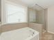 Bright bathroom features a soaking tub under a window and a glass-enclosed shower at 4912 Grace View Dr, Pineville, NC 28134