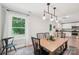Bright dining area with a wooden table, modern lighting, and a view of the green outdoors through a large window at 507 Newsome Rd, Salisbury, NC 28146
