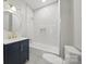 Bathroom featuring navy vanity, shower and tub with white tile surround, and gold fixtures at 522 Alexander St, Statesville, NC 28677