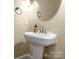Powder room featuring a pedestal sink, oval mirror, and stylish fixtures for a modern touch at 6011 Nw Village Nw Dr, Concord, NC 28027