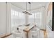 Bright dining area with natural light, a long wooden table, white chairs, and sheer white curtains at 621 Poindexter Dr, Charlotte, NC 28209