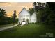 Stunning exterior of white home with lush green lawn, mature trees, and a driveway leading to the property at 621 Poindexter Dr, Charlotte, NC 28209