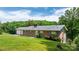 Brick home showcasing a well-manicured lawn, mature trees, and an attached garage, perfect for countryside living at 6256 Monford Dr, Conover, NC 28613