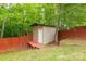 Charming wooden shed with a red access ramp inside a fenced area, set among mature trees at 8120 Vermilion Dr, Charlotte, NC 28215
