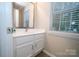 This home's half bathroom has a sink with vanity and a mirror, plus a window at 8125 Sheringham Way, Charlotte, NC 28227