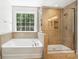 Bathroom featuring a tub and glass enclosed shower with beautiful window view at 8521 Aspen Ct, Charlotte, NC 28227