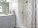 Well-lit bathroom featuring a gray vanity, framed mirror, modern fixtures, and a shower with a patterned curtain at 9300 Surrey Rd, Mint Hill, NC 28227