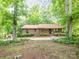 Charming brick home nestled among mature trees, boasting a covered front porch and lush landscaping at 9300 Surrey Rd, Mint Hill, NC 28227