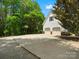 View of attached garage with driveway and a basketball hoop, surrounded by lush trees at 1010 Arabian Farm Rd, Clover, SC 29710