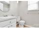 Clean bathroom featuring a toilet and vanity, complemented by a window for natural light at 10945 Wiltshire Ln, Charlotte, NC 28262