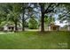 Lush backyard featuring mature trees, a storage shed, and a stone patio with seating area at 1109 S Highland Ave, Landis, NC 28088