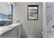 Bright bathroom featuring white shiplap walls, a marble-look sink, and a window overlooking greenery at 1109 S Highland Ave, Landis, NC 28088