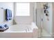 Bright bathroom featuring a soaking tub and a separate glass-enclosed shower at 1109 Woodwinds Dr, Waxhaw, NC 28173
