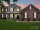 Charming two-story home with a well-manicured lawn and a welcoming front porch with black shutters at dusk at 1109 Woodwinds Dr, Waxhaw, NC 28173