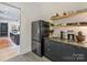Kitchenette boasts stainless appliances, floating shelves, and view to kitchen at 112 Manning Dr, Charlotte, NC 28209