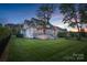 A beautifully landscaped backyard at dusk, featuring a well-maintained lawn and a two-story home at 118 Tuscany Trl, Mooresville, NC 28117